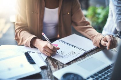 Closeup shot of an unrecognisable businesswoman writing notes at a coffee shop